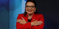 Präsidentin Xiomara Castro. Sie fasst sich mit den Händen an die Oberarme, die Arme sind also über Kreuz. Sie trägt ein rotes Jackette.