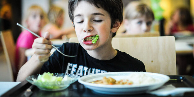 Ein Kind isst in einer Kantine.