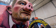 in Motivwagen, der Bundesfinanzminister Christian Lindner als Sparschwein mit der Schuldenbremse zeigt, steht beim Richtfest für den Kölner Rosenmontagszug im Karnevalsmuseum.
