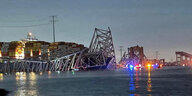 Die Metallpfeiler der eingestürzten Autobahnbrücke ragen aus dem Wasser. Im Hintergrund sind die gestapelten Container des Schiffs "Dali" erkennbar.