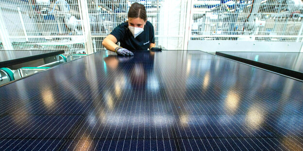 Eine Mitarbeiterin begutachtet in der Endkontrolle einer Produktionslinie für Solarmodule im Werk der Meyer Burger Technology AG in Freiberg ein Solarmodul