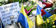 Neben dem Einkaufszentrums, an dem zwei Männer aus der Ukraine getötet worden sind, haben Menschen Blumen und Plakate niedergelegt